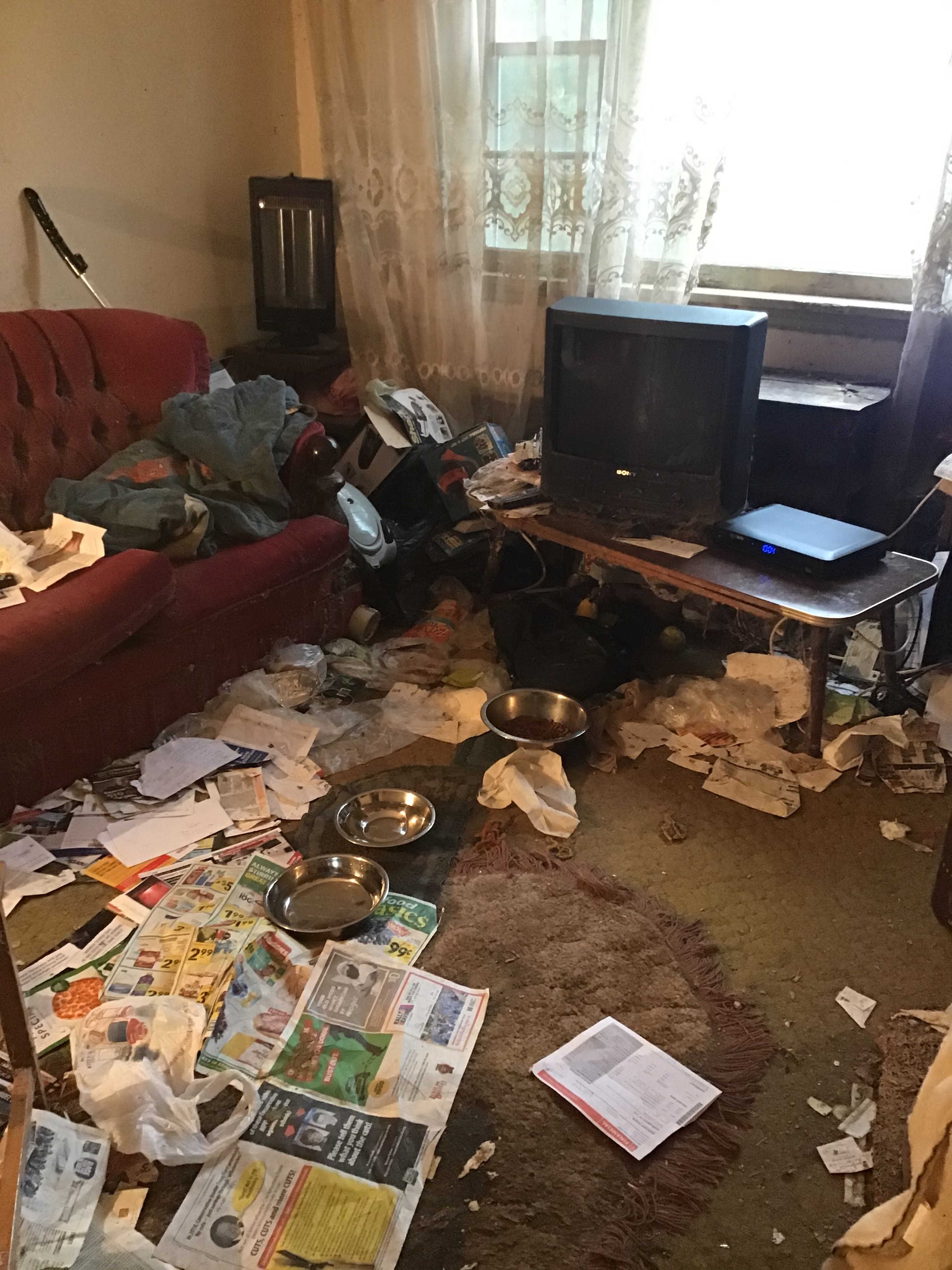 Cluttered living room with scattered debris and belongings