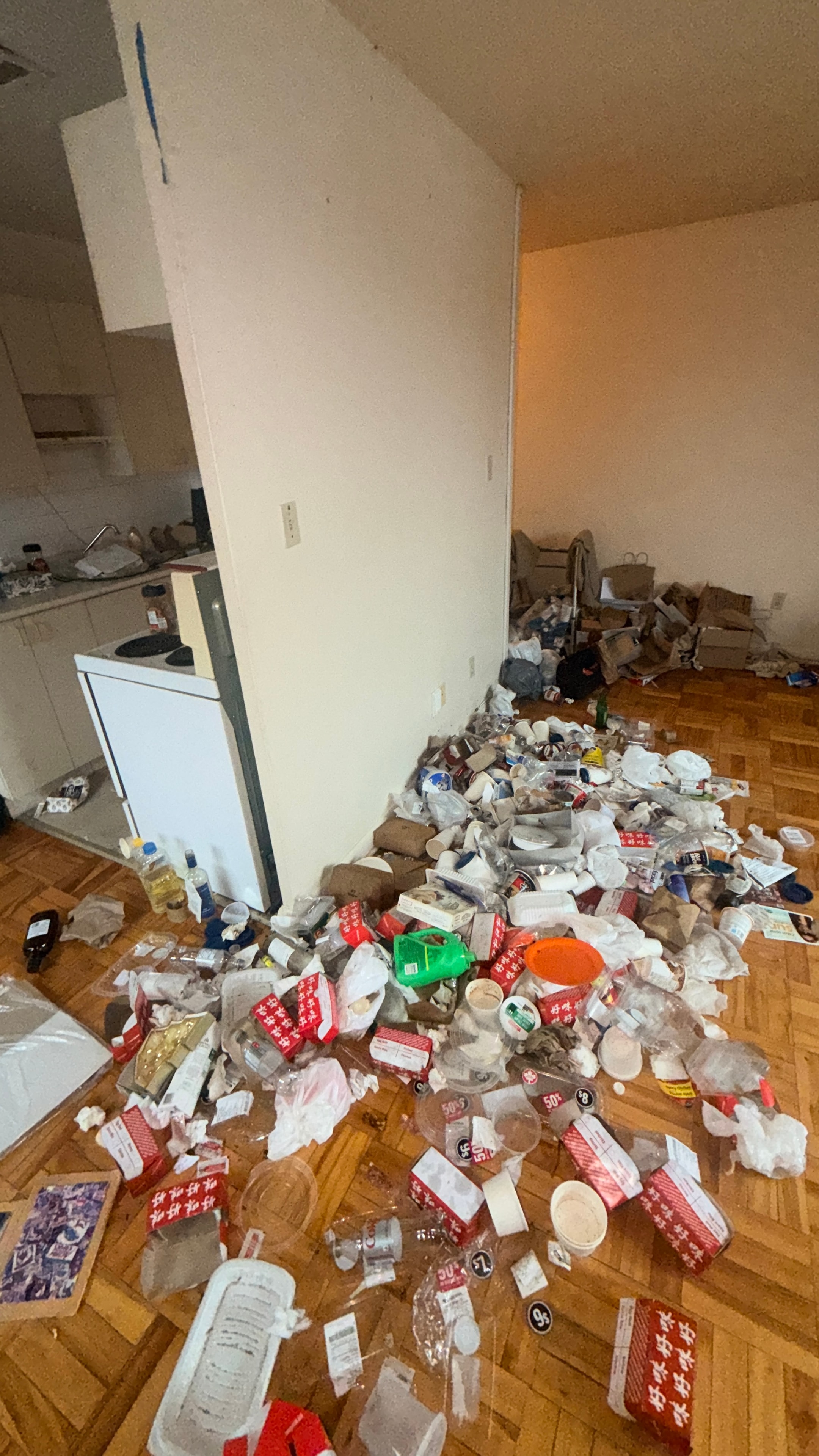Cluttered apartment floor with accumulated trash and belongings